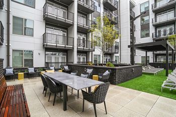 An outdoor patio with a table and chairs in front of an apartment building